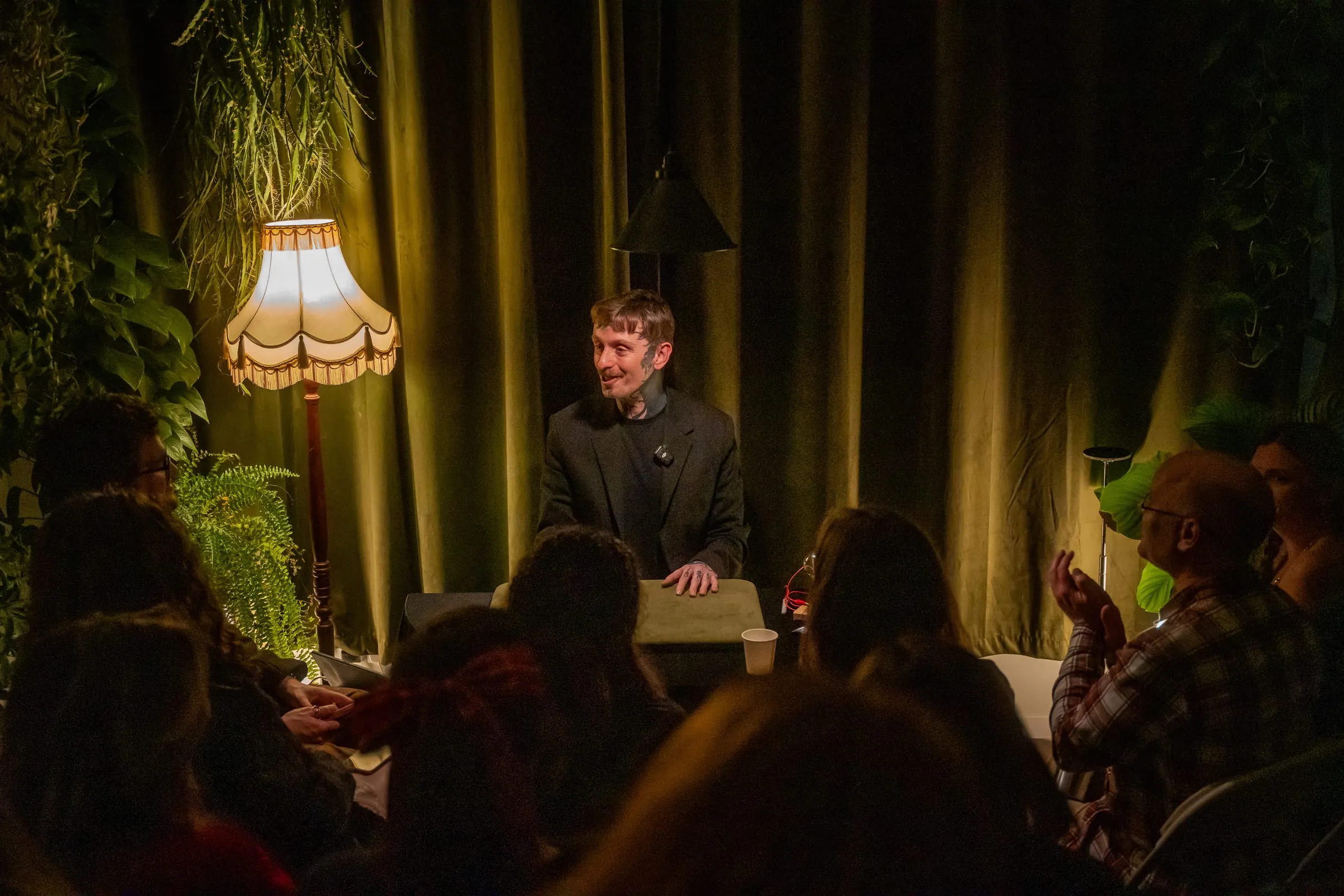 A magician performs close-up magic by lamplight to a candlelit audience at Bristol Magic Theatre