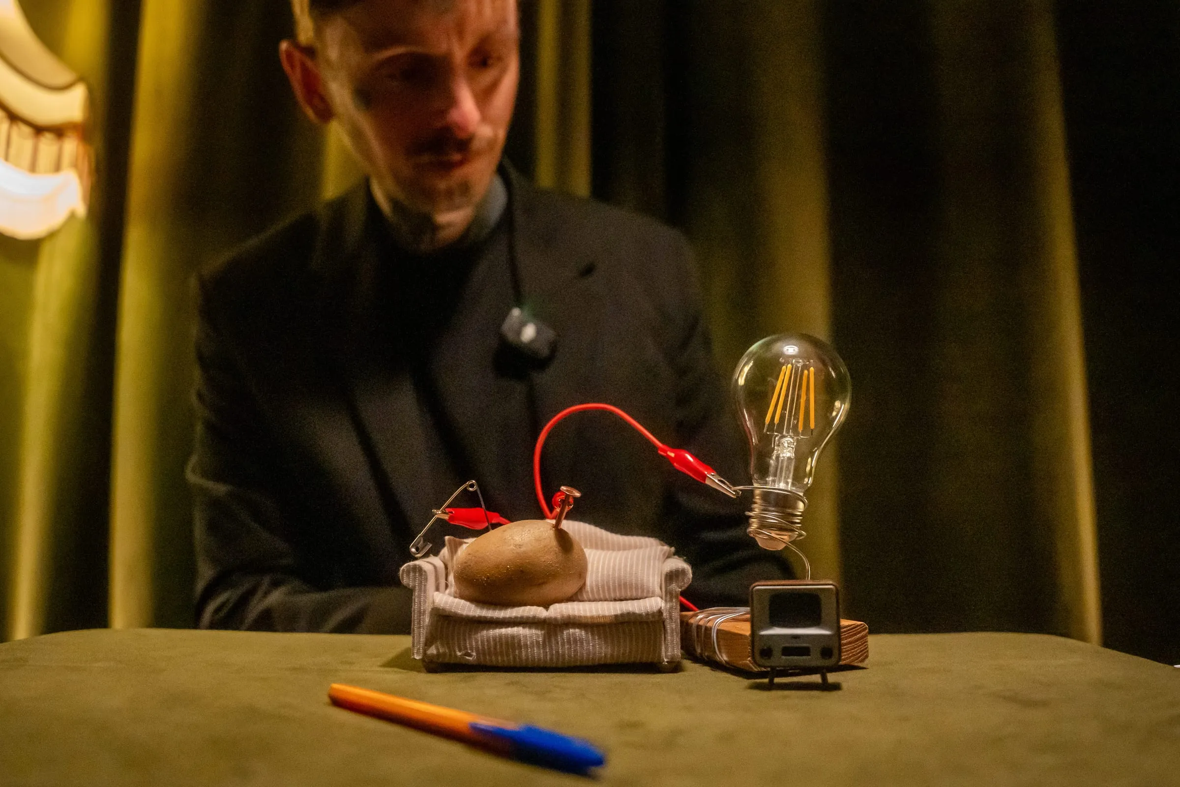 A potato wired to a light bulb on a miniature sofa during a surreal routine