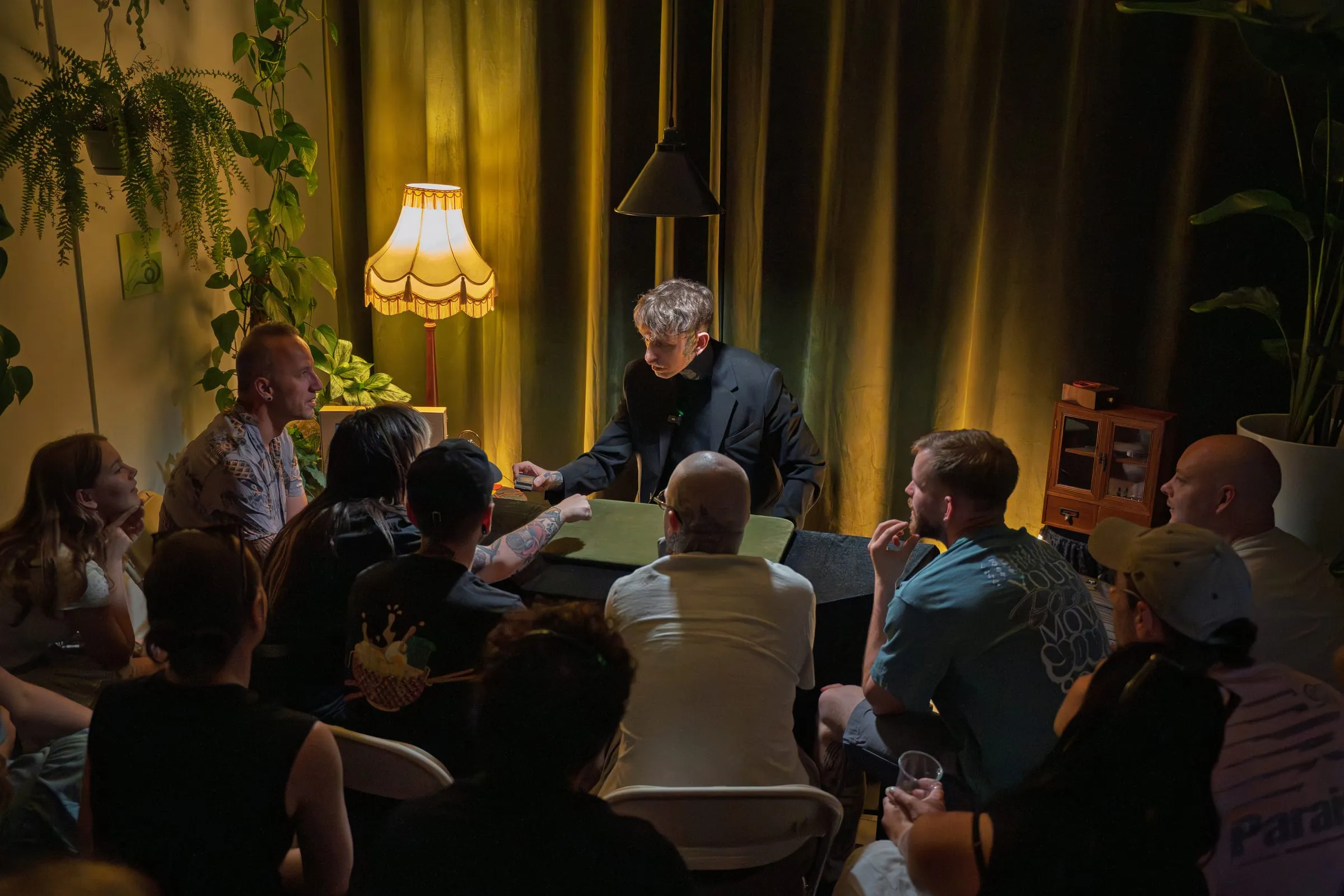 The intimate single-table theatre full of guests around the magician during a show